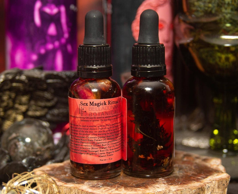 Two bottles of 'Sex Magick Ritual' with droppers on a wooden surface, surrounded by mystical items.