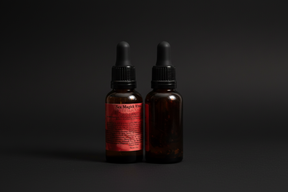 Dropper bottle with Sex Magick Ritual Oil in it on a black cloth,.