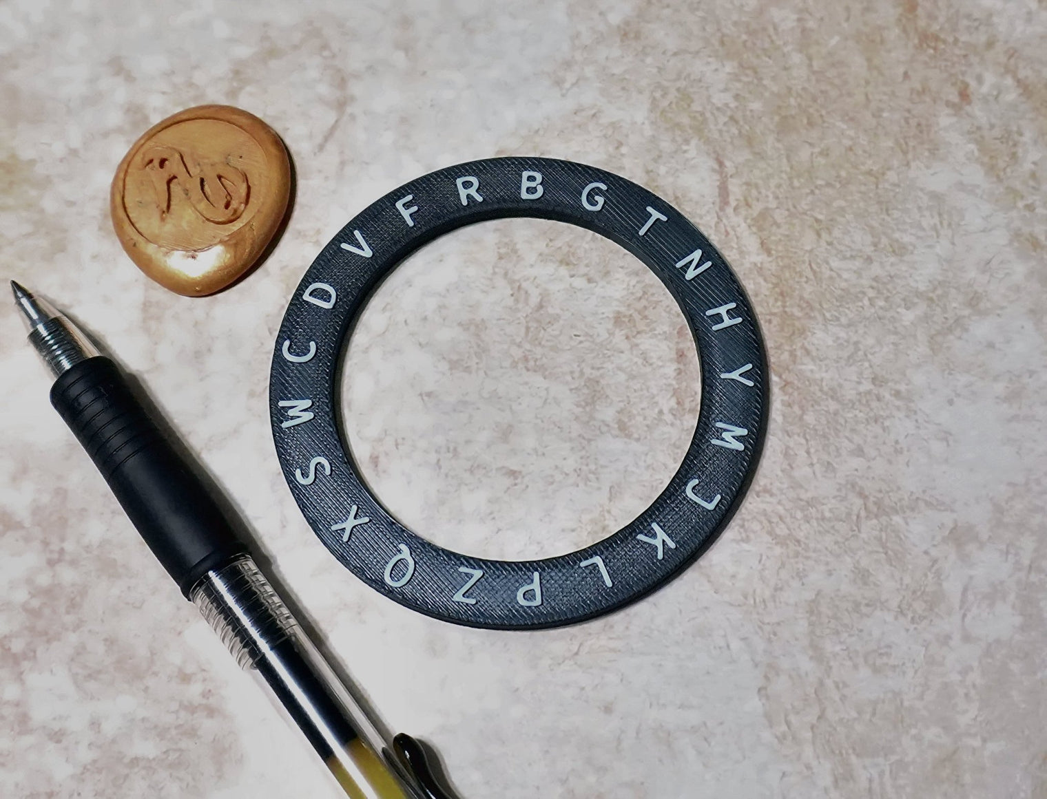 Circular object with lettering, pen, and cookie on a beige surface
