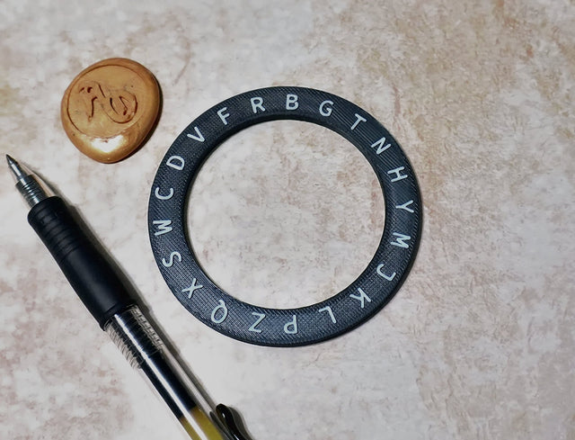 Circular object with lettering, pen, and cookie on a beige surface