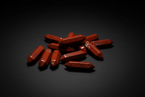 Hand holding red stones on a wooden surface