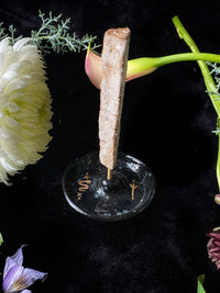 Decorative item on a black stand with flowers in the background