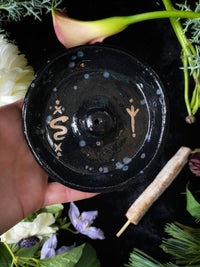 Black ceramic dish with floral and plant elements on a dark background