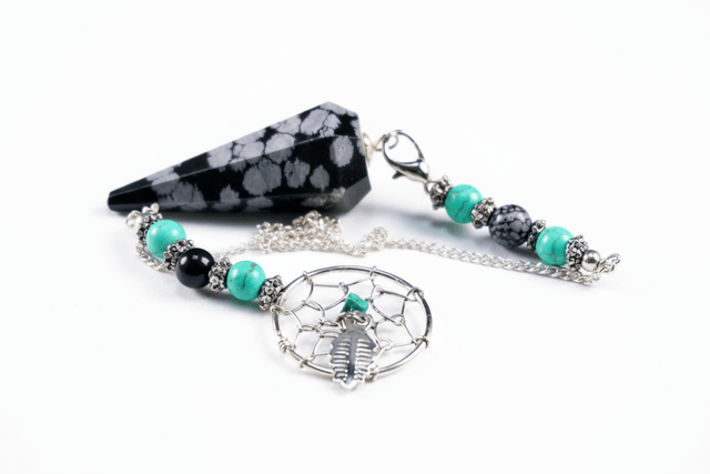 a snowflake obsidian pendulum on a white background