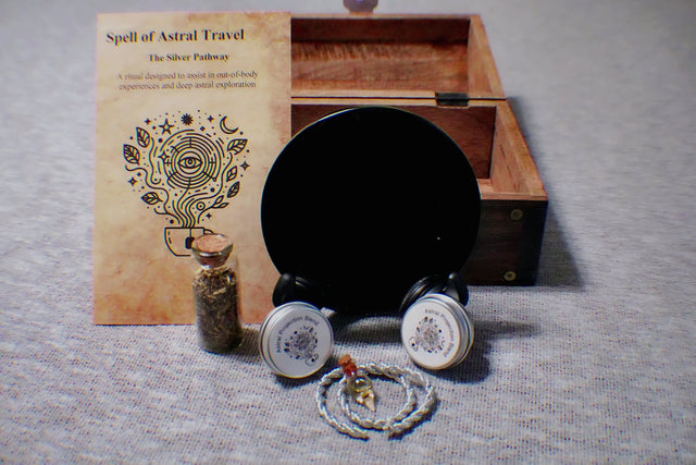 Magical spell kit with book, obsidian mirror, and other items on a gray surface