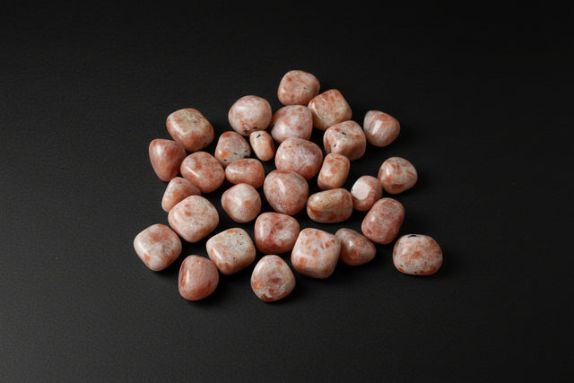 Pile of pink stones on a gray surface with rulers for scale.