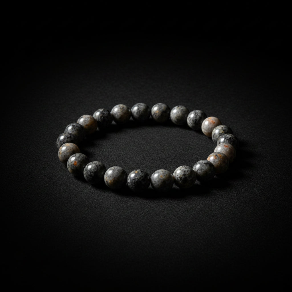A beaded bracelet made of polished gray and white stones, displayed on a light black