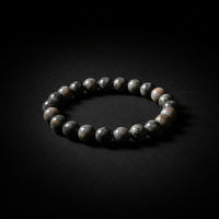 A beaded bracelet made of polished gray and white stones, displayed on a light black