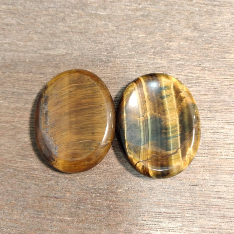 Two tiger eye stones on a wooden surface