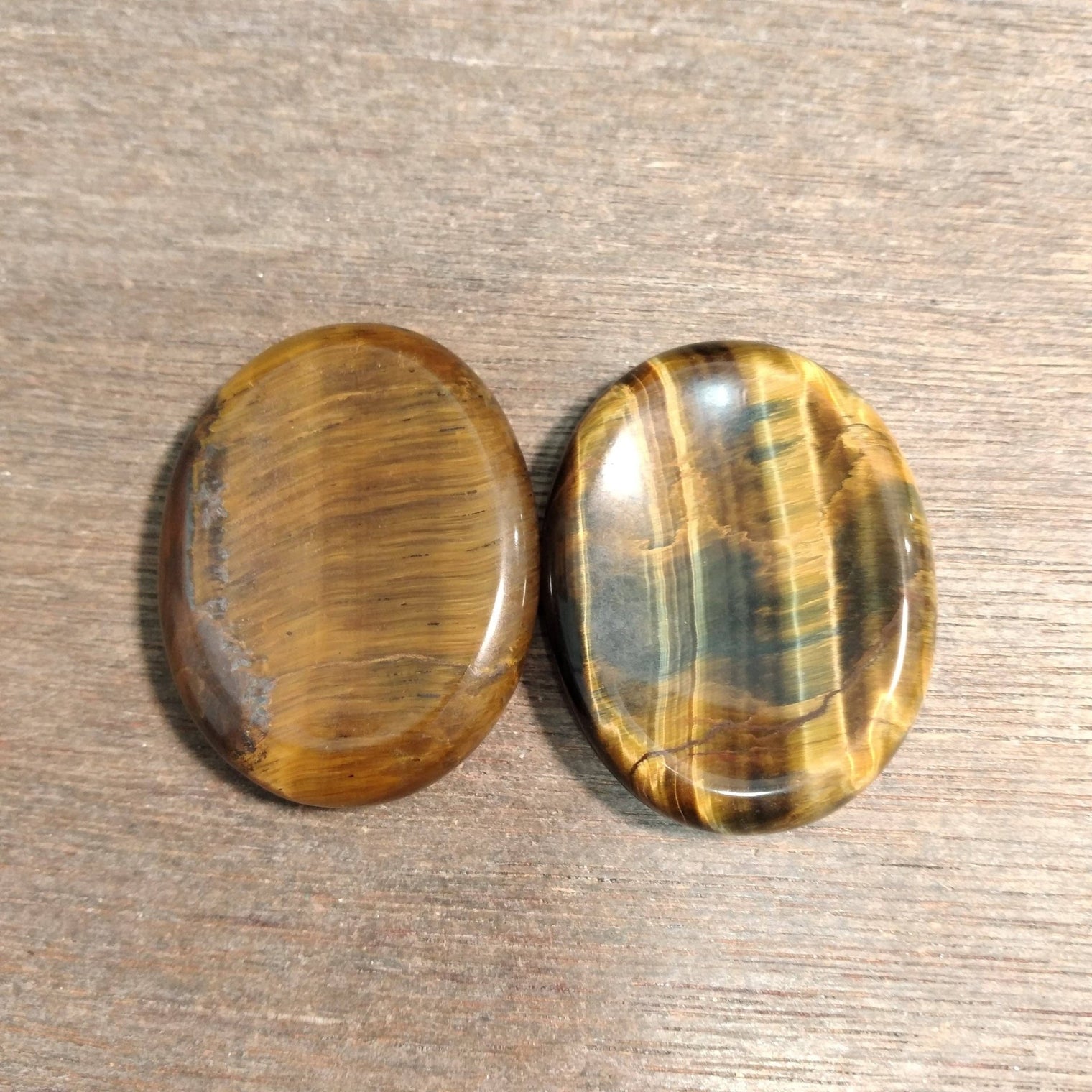 Two tiger eye stones on a wooden surface