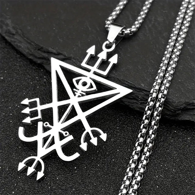 Silver pendant with intricate design on a black stone surface