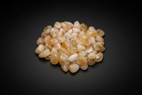 Pile of small, round, beige stones on a white background