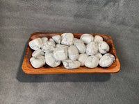 Wooden tray with white marbled stones on a gray background
