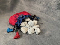 Red and blue drawstring bag filled with white stones on a gray surface