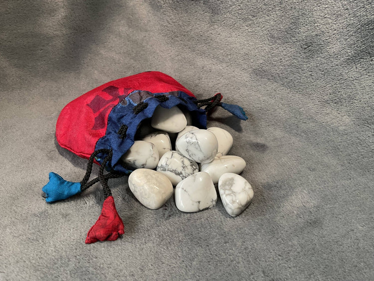 Red and blue drawstring bag filled with white stones on a gray surface