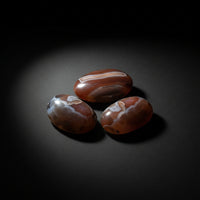 Representative assortment of polished Volcano Agate palm stones with gray, white, brown, and reddish banding