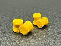 Four yellow earplugs on a gray surface