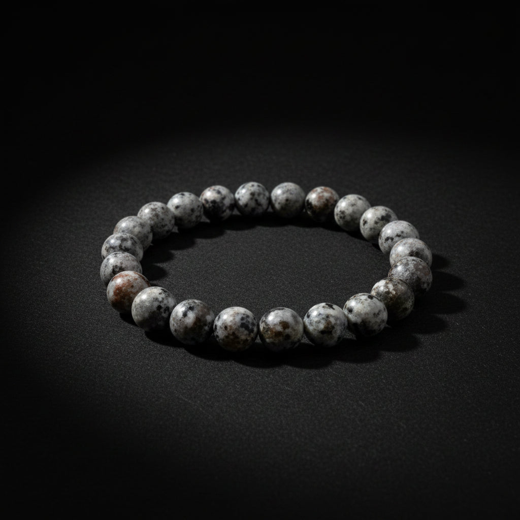 A beaded stretch bracelet made of polished gray agate or jasper stones with white marbling, shown on a neutral light gray background.
