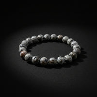 A beaded stretch bracelet made of polished gray agate or jasper stones with white marbling, shown on a neutral light gray background.
