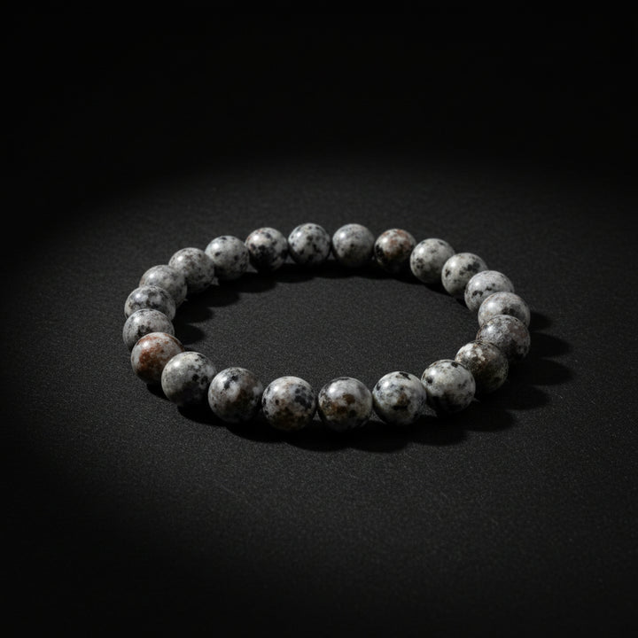 A beaded stretch bracelet made of polished gray agate or jasper stones with white marbling, shown on a neutral light gray background.